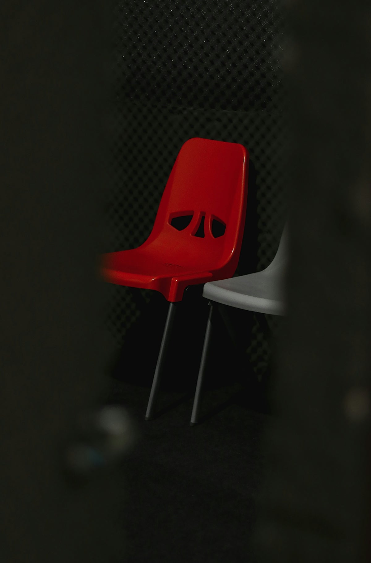 a red chair with eyes on it sitting next to a white chair