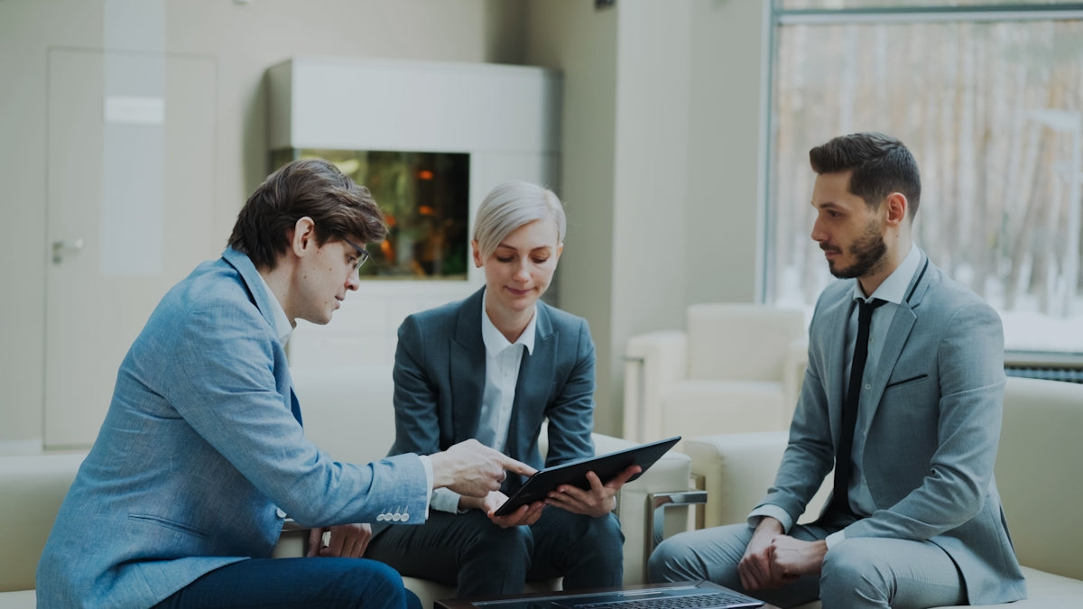 Three professionals discussing a tablet in a modern office.