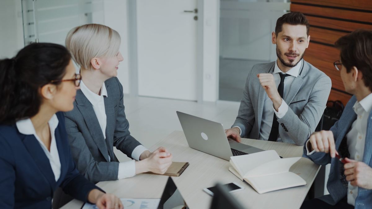 Four professionals in a business meeting around a table.