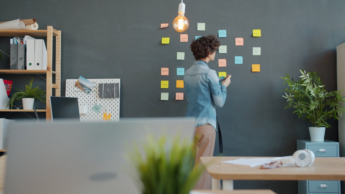 Woman adding sticky notes to a dark wall.