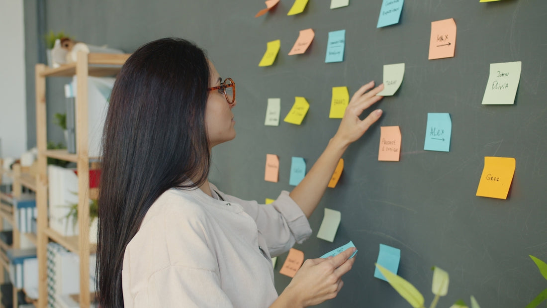 Woman placing sticky notes on a dark wall.