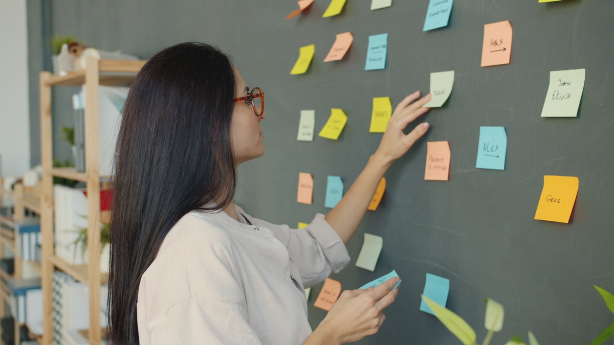 Woman placing sticky notes on a dark wall.